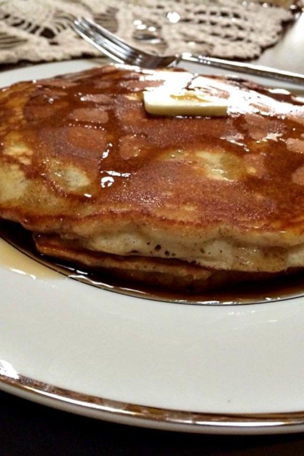 a stack of pancakes with syrup and butter on a white plate next to a fork