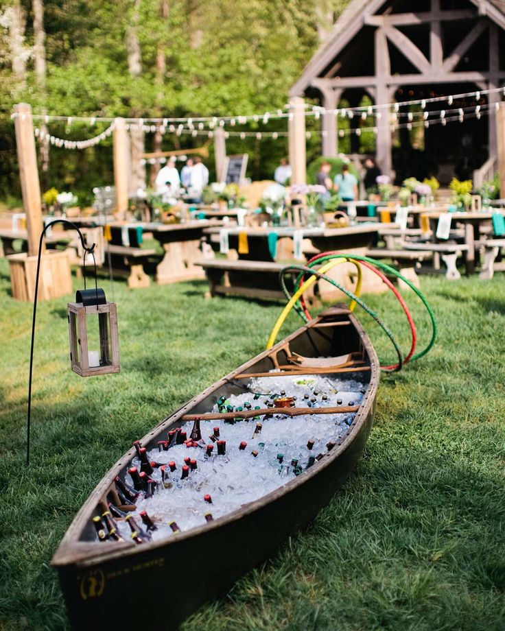 a row boat is sitting on the grass in front of an outdoor venue with tables and chairs