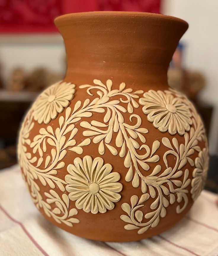 a brown vase with white flowers painted on it