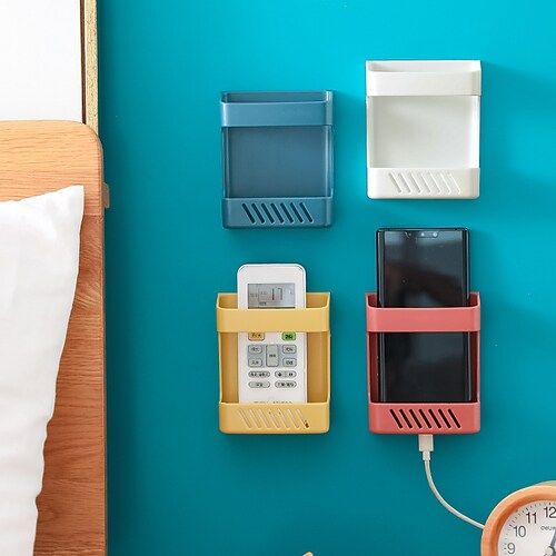 three cell phones are attached to the wall next to an alarm clock and phone charger