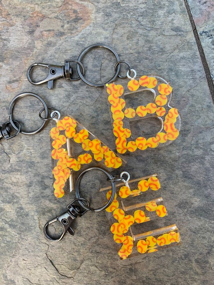 two orange and yellow beaded key chains on top of a stone slab with metal hooks