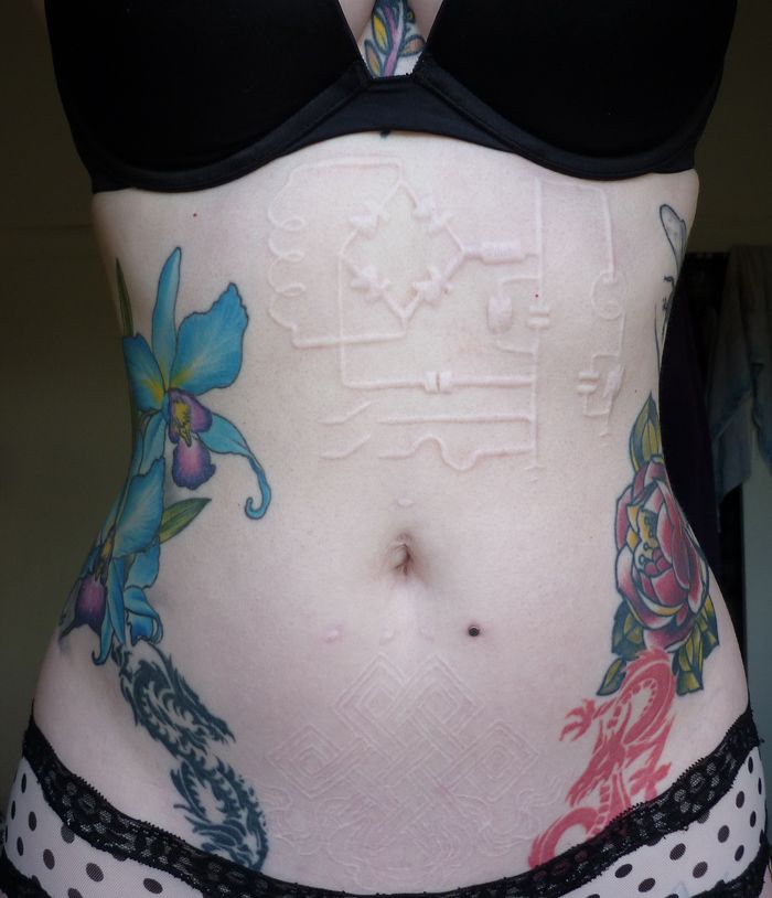 a woman's stomach with tattoos on it