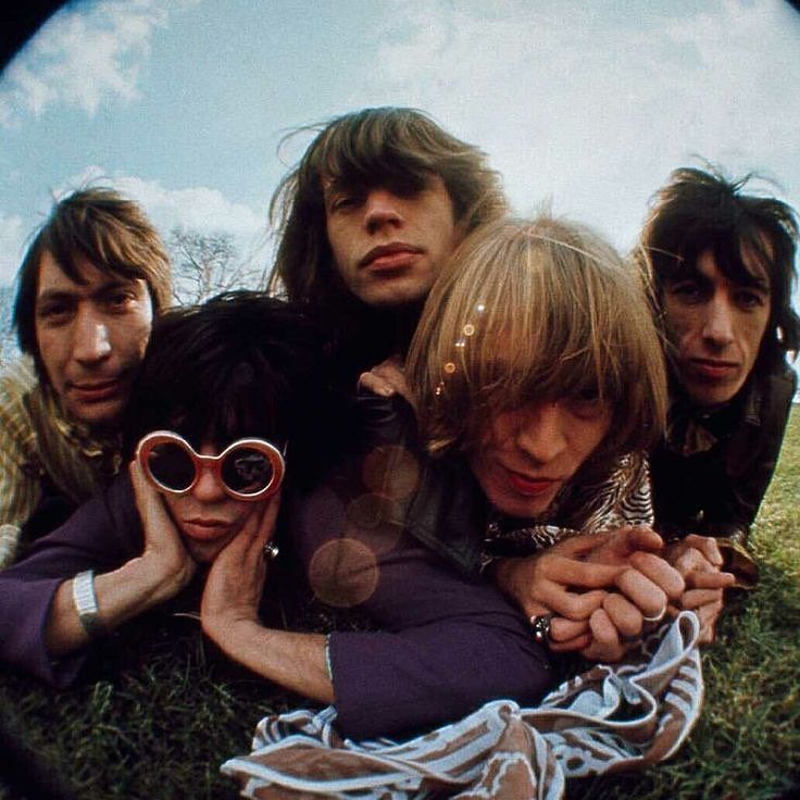 four people laying on the ground with one holding a cell phone and looking at it