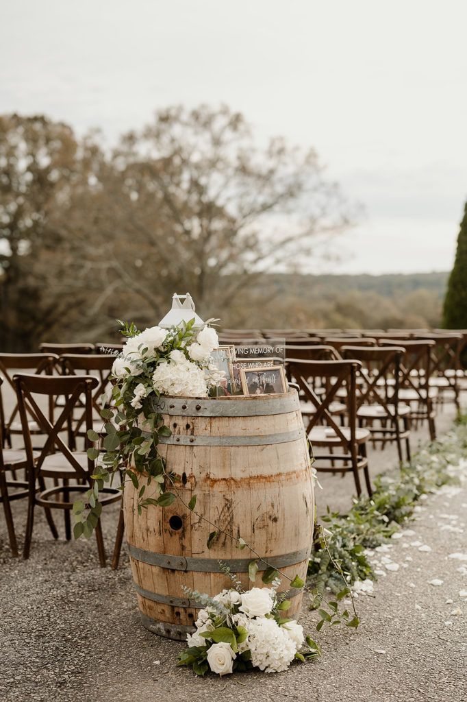 a wooden barrel with flowers and greenery on the ground next to rows of chairs