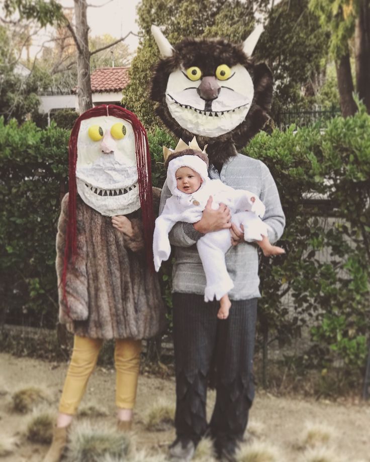 a man and woman holding a baby in front of a cat mask