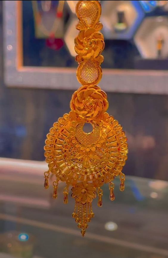 an intricately designed yellow necklace hanging from a glass display case in a store window