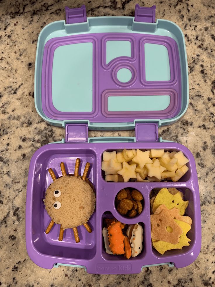 a purple lunch box filled with food on top of a counter