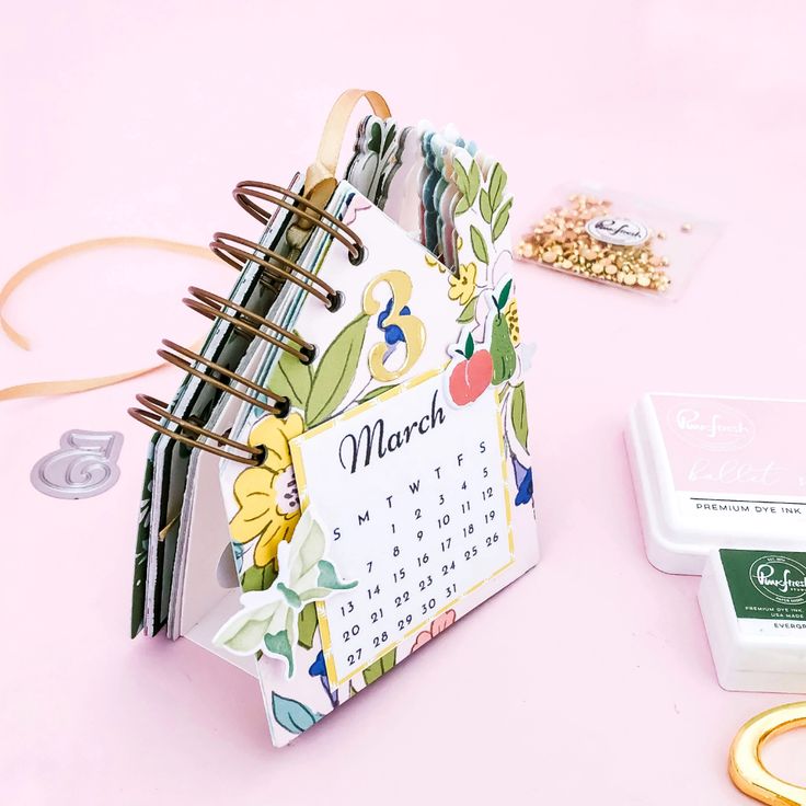 a desk with a calendar, ring binder and other office supplies on the table