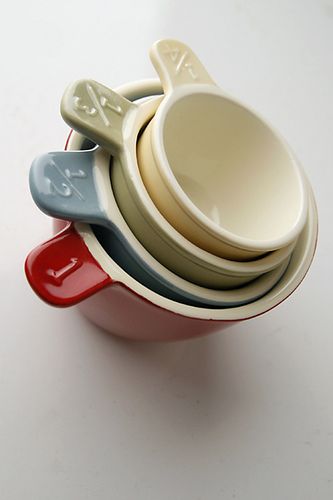 a stack of four ceramic bowls with spoons in them on a white table top