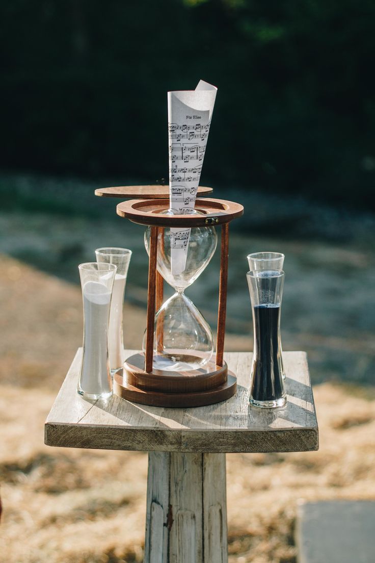 an hourglass and some glasses are sitting on a small table with notes in it