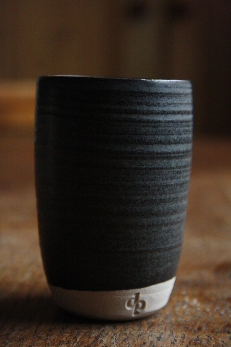 a black cup sitting on top of a wooden table