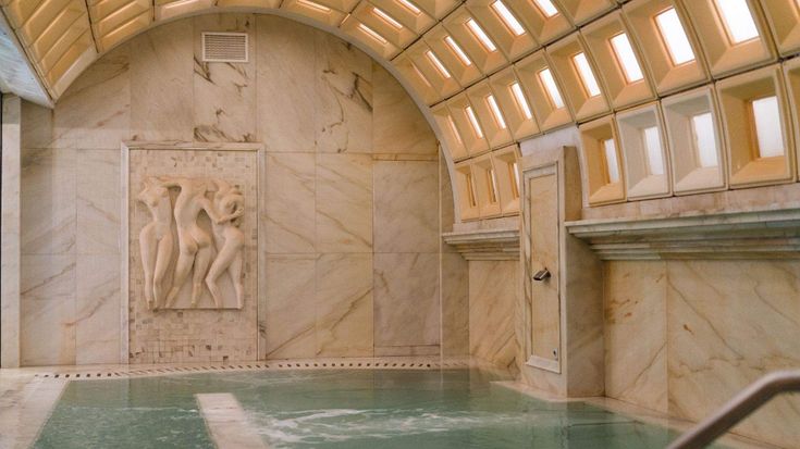 an indoor swimming pool with statues on the wall