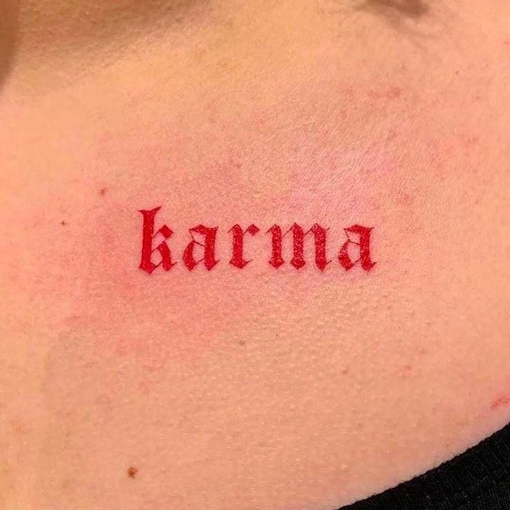 a woman with a tattoo that says karma on her chest and has the word written in red ink