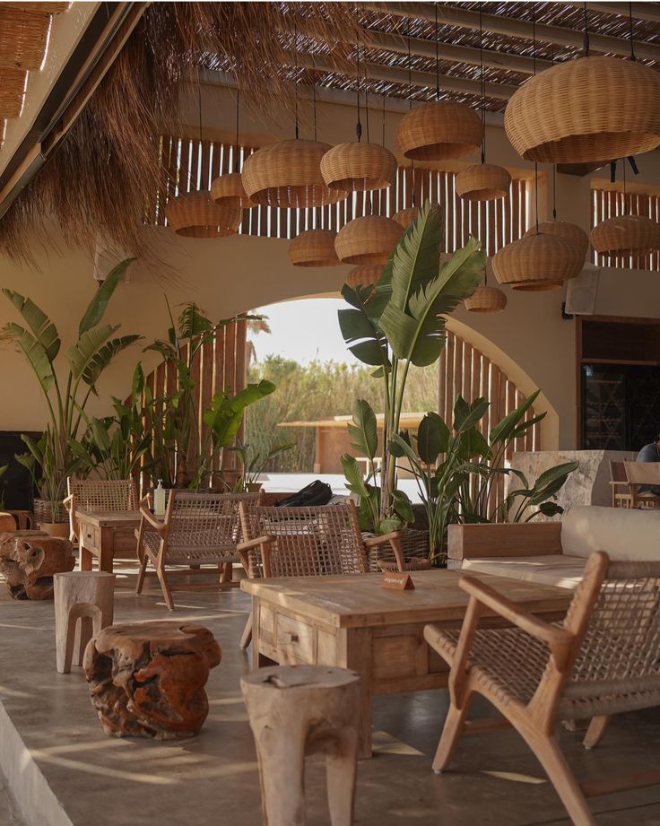 the inside of a restaurant with tables, chairs and potted plants hanging from the ceiling