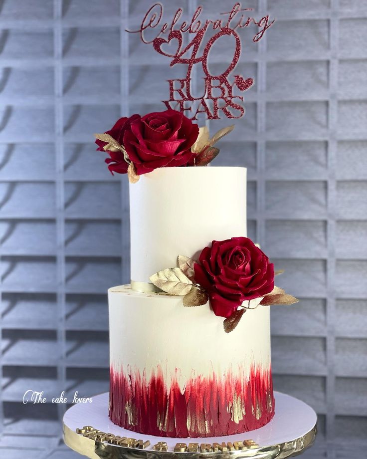 a white and red cake with two roses on top