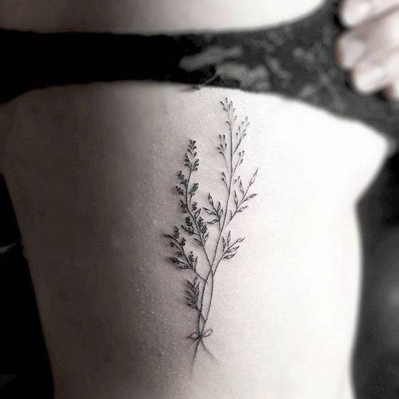 a woman's stomach with a small plant tattoo on it