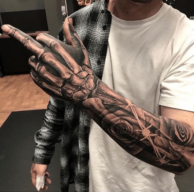 a man with a tattoo on his arm holding up a hand that has a rose in it