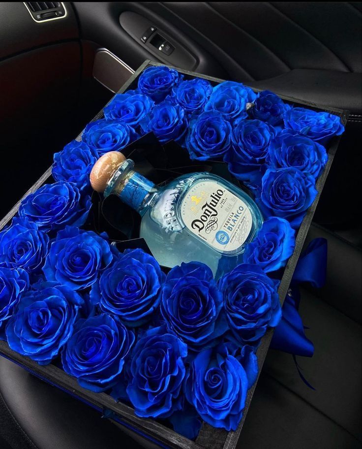 blue roses and a bottle of gin in a car seat