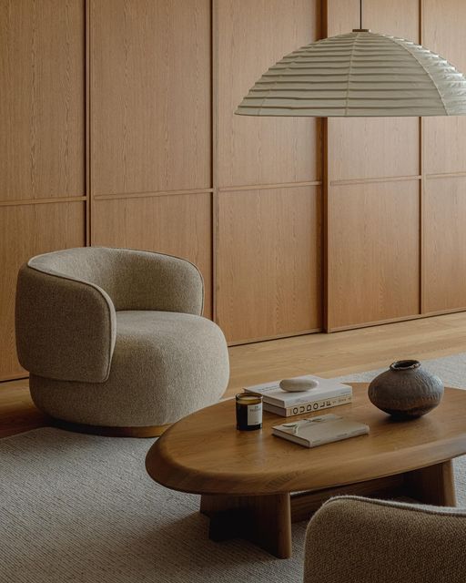 a living room with two chairs and a table in front of wooden paneled walls