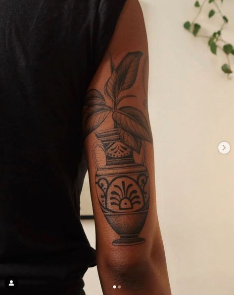 a man with a tattoo on his arm has a potted plant in the vase