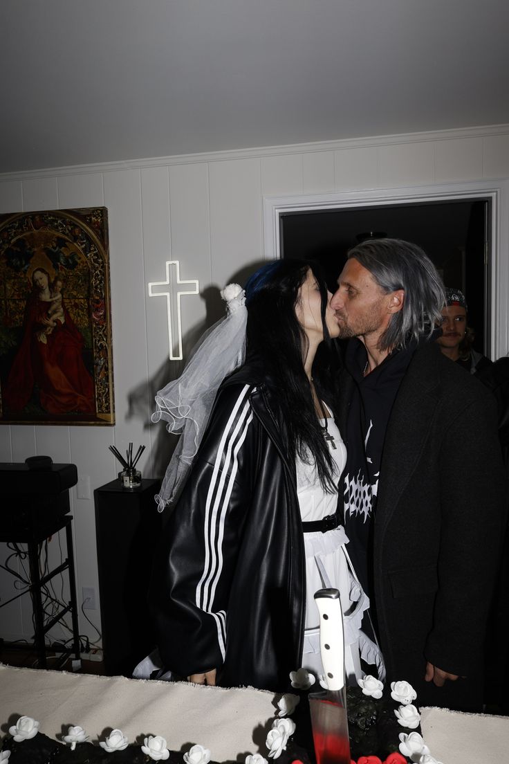 a man and woman kissing in front of a cake