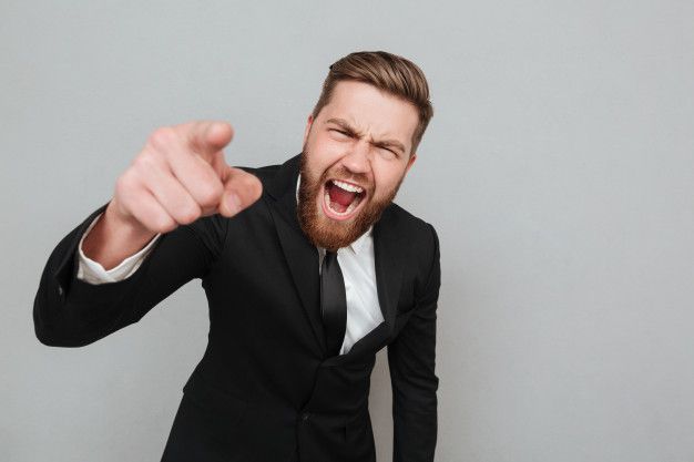 a man in a suit and tie pointing his finger at the camera with an angry look on his face