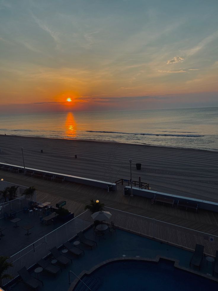 the sun is setting over the beach and ocean