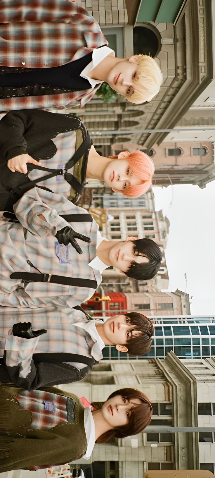 four young people standing in front of a tall building with their hands on their hipss