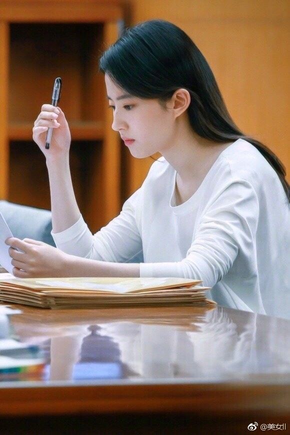 a woman sitting at a table with a book and pen in her hand