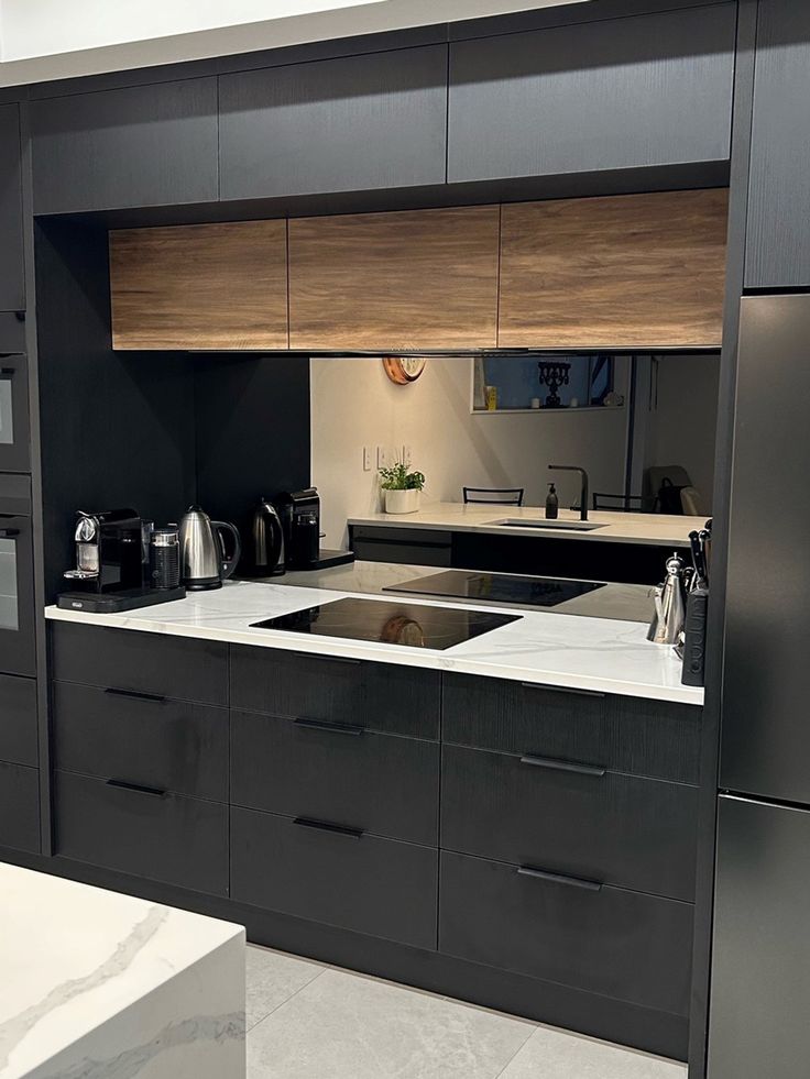 The reflective glass surface on this splashback adds a touch of elegance, making the kitchen feel more spacious and sophisticated. Perfect for cooking up a storm or simply admiring its beauty, our 'smokey grey' glass splashback is the ultimate statement piece that enhances the ambiance of the kitchen Splashback Ideas For Grey Kitchen, Mirror Glass Splashback Kitchen, Black Mirror Splashback Kitchen, Dark Grey And Oak Kitchen, Splashback Ideas For White Kitchen, Modern Splashback Kitchen, Black Glass Splashback Kitchen, Modern Kitchen Splashback Ideas, Smoked Mirror Splashback Kitchen