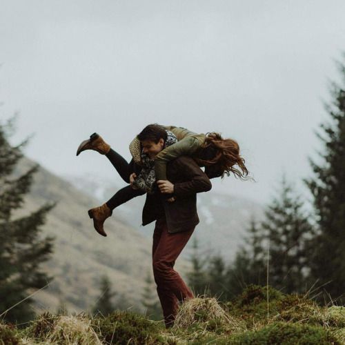 a man carrying a woman on his back in the mountains