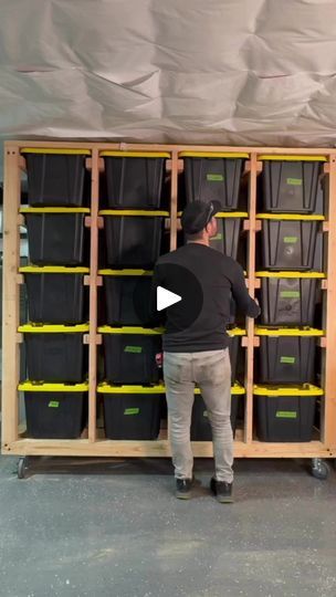 a man standing in front of a shelf filled with plastic bins and yellow tape