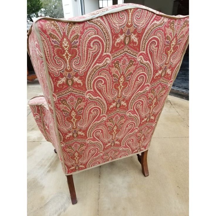 a red and gold patterned chair sitting on top of a floor