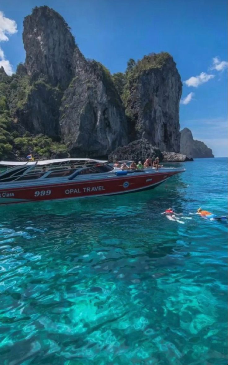 people swimming in the ocean next to a boat