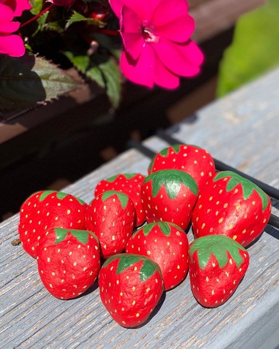 a group of strawberries sitting on top of a wooden table next to pink flowers