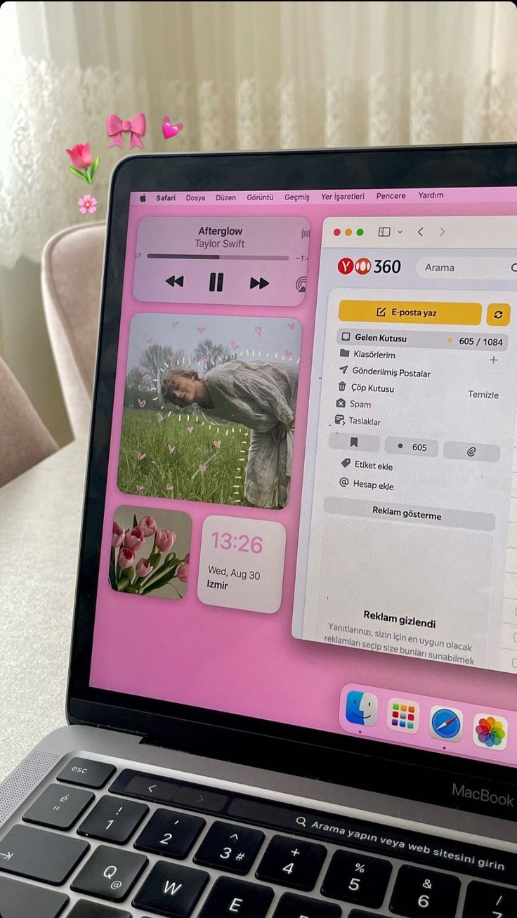 an open laptop computer sitting on top of a white table next to a pink flower