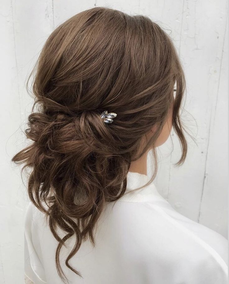 a woman with brown hair wearing a white shirt and silver hair pins in her hair