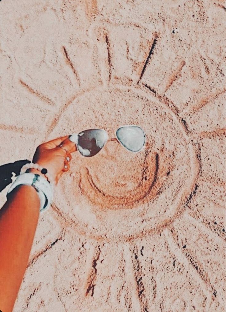 a person wearing sunglasses standing in the sand