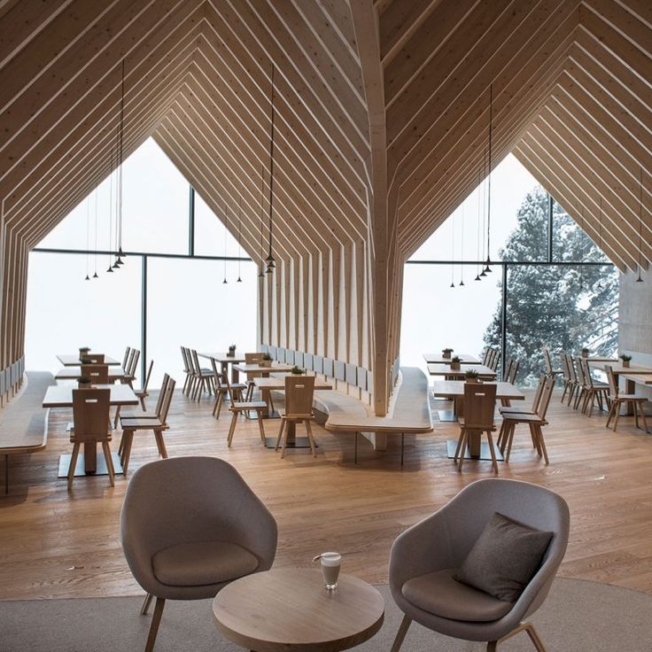 two chairs and tables in a room with wooden walls, windows, and wood flooring