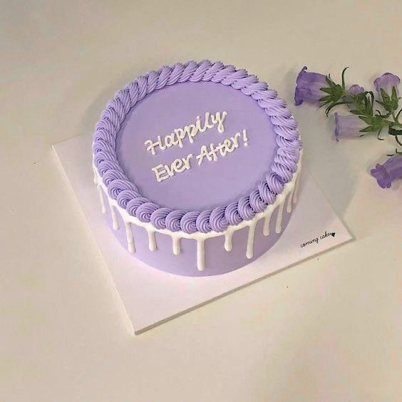 a purple birthday cake with white icing and flowers