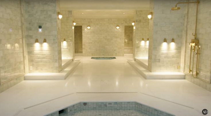 a large indoor swimming pool with lights on the walls and in between it is a jacuzzi tub