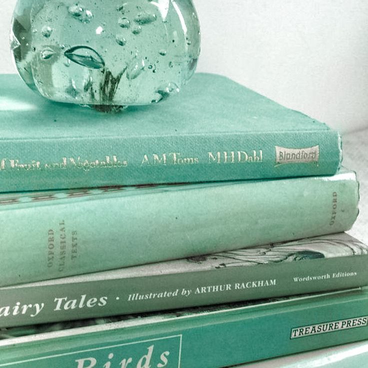 three books stacked on top of each other with a glass ball sitting on top of them