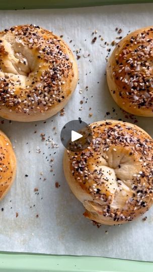 four bagels with sesame seeds and poppy seed sprinkles on a baking sheet