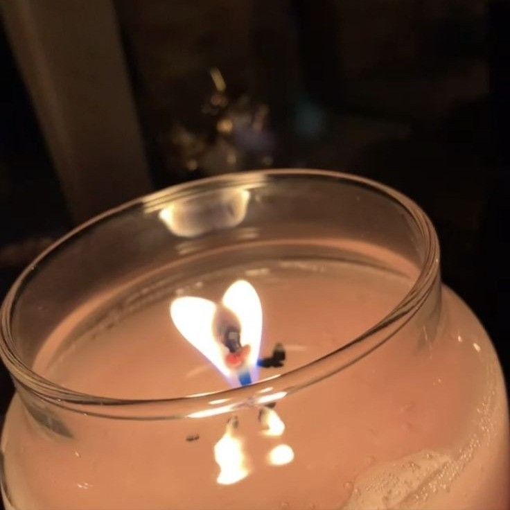 a lit candle in a glass bowl on a table