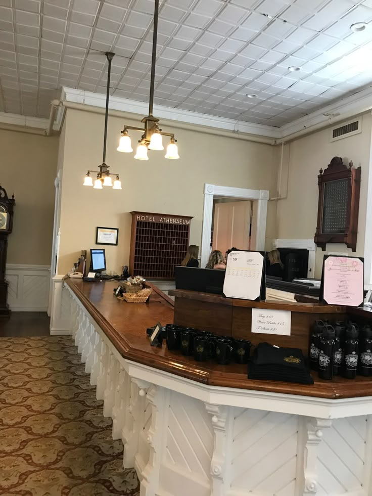 the front desk of an office with several items on it and lights hanging from the ceiling