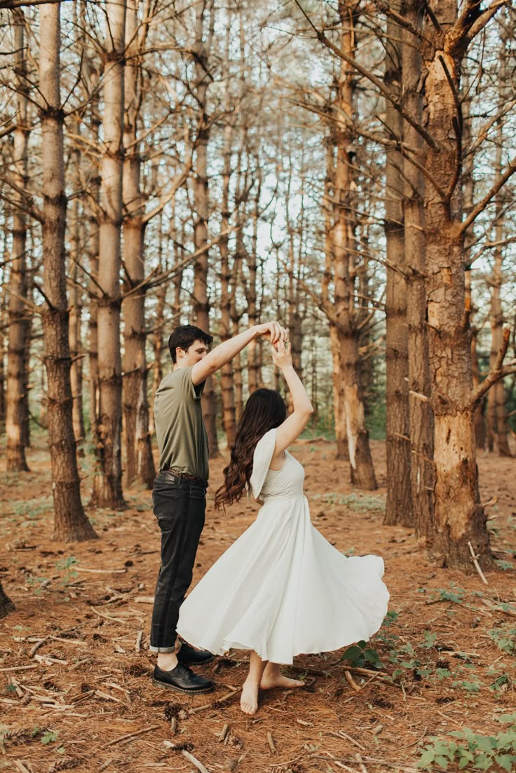 a man and woman dancing in the woods