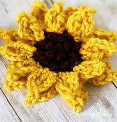 a crocheted sunflower sitting on top of a wooden table