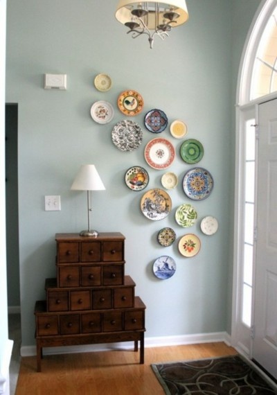 a room with plates on the wall and a dresser in front of it that is next to a doorway