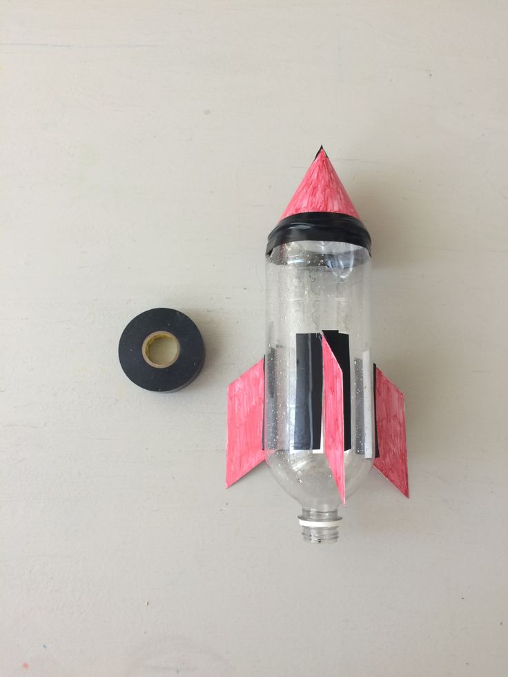 a paper rocket ship next to a tape dispenser on a white surface