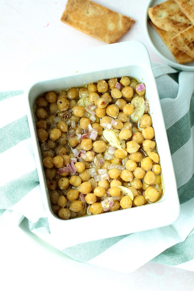 a white bowl filled with chickpeas next to crackers